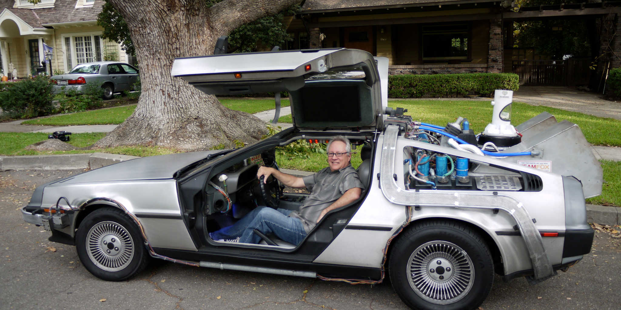 Filmmaker John McDonald siiting in front of the Peeping Tom tree in a replica of the Back to the Future DeLorean time machine